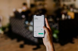 Person holding smartphone displaying Amazon stock price chart in a blurred indoor setting, focusing on financial growth